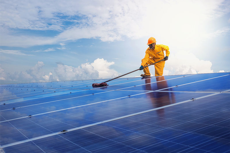 Ein Mann reinigt grad die Solarzellen